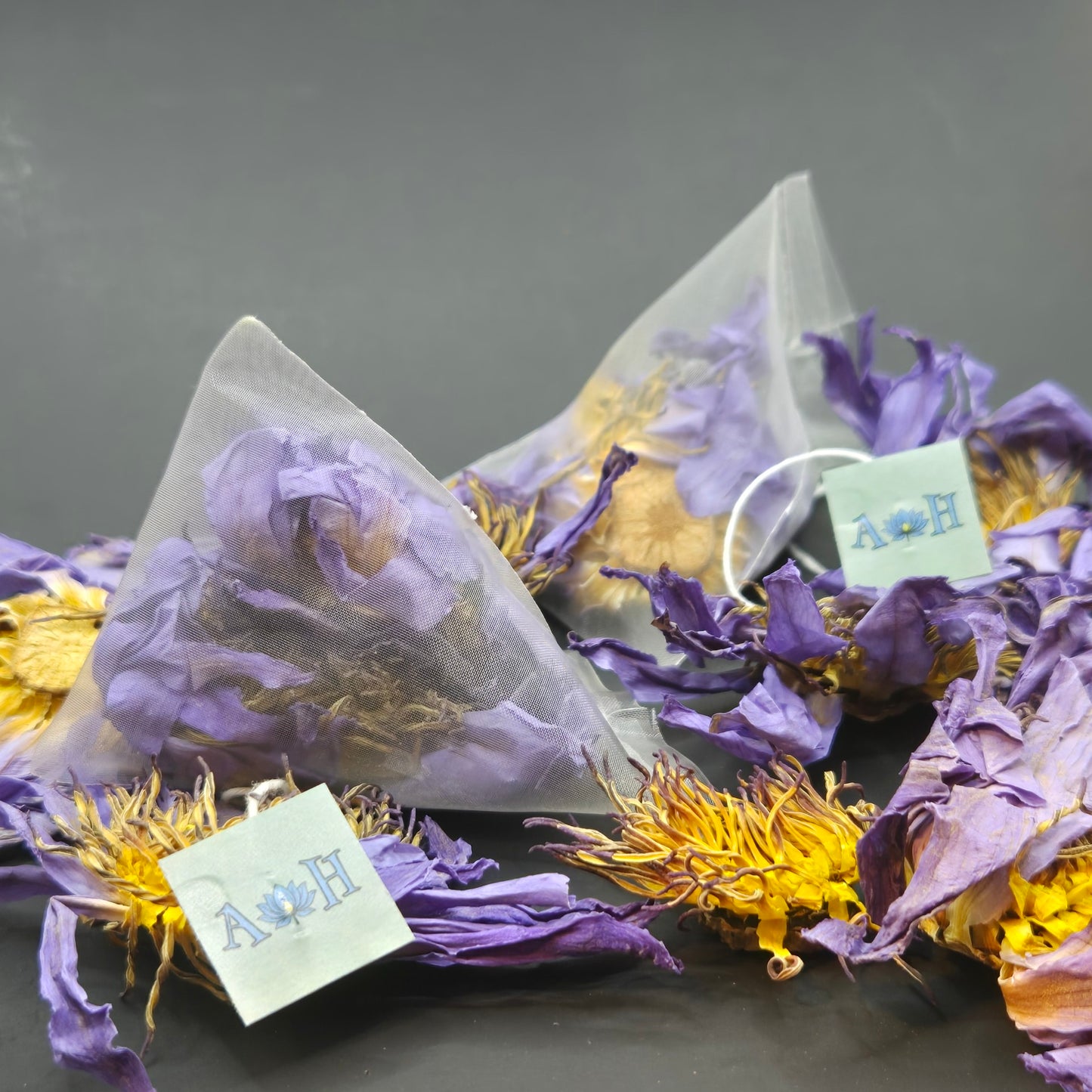 Blue lotus pyramid tea bags by Astral Herbal on a black background with dried blue lotus flowers.