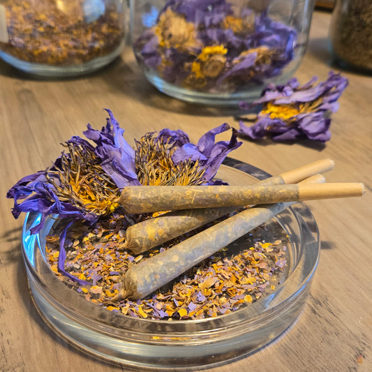 Three Astral Herbal pre rolls on a glass jar filled with dried blue lotus petals