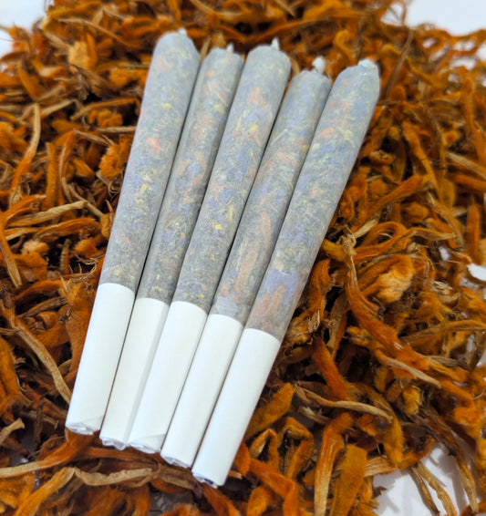 Five herbal pre rolls by Astral Herbal on a bed of wild dagga flowers on a white background.