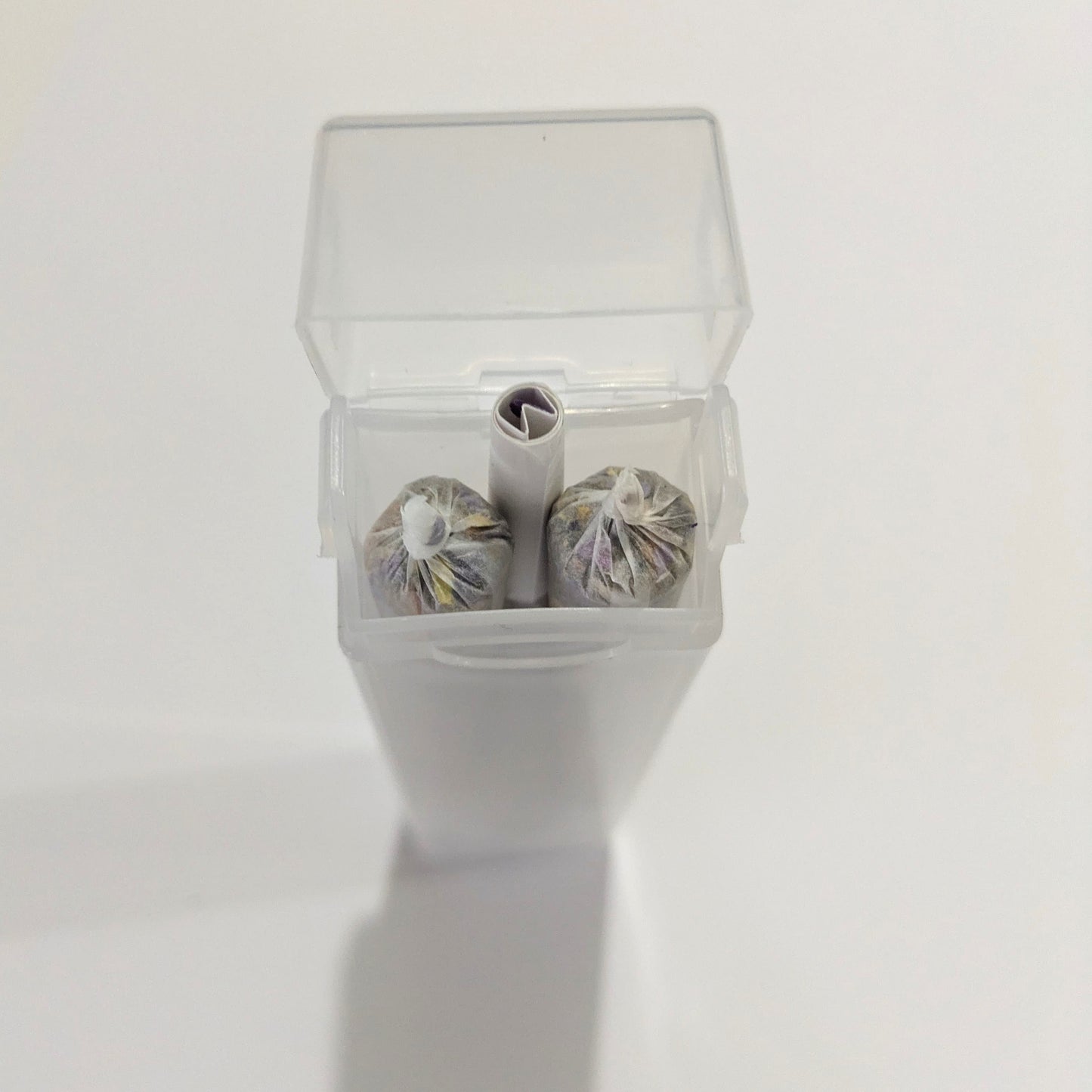 Three herbal cigarette pre rolls in a clear plastic container on a white background by Astral Herbal.