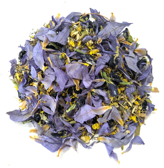 A mound of dried blue lotus flower petals, chamomile, and butterfly pea flowers on a white background by Astral Herbal.