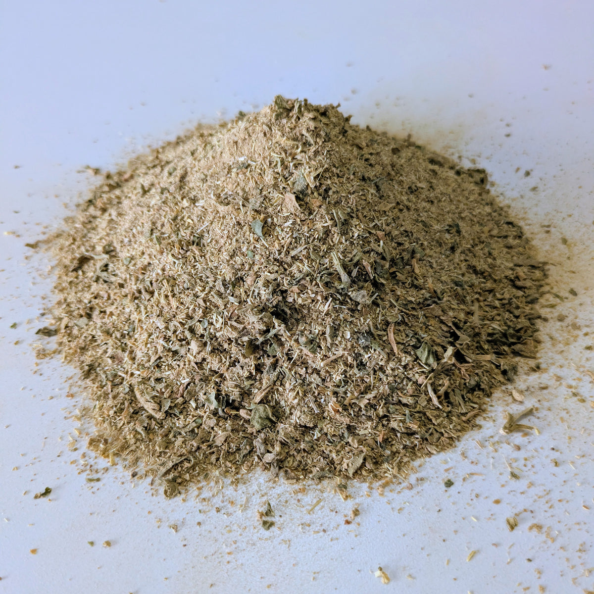 Heap of greenish-brown kanna powder on a white background