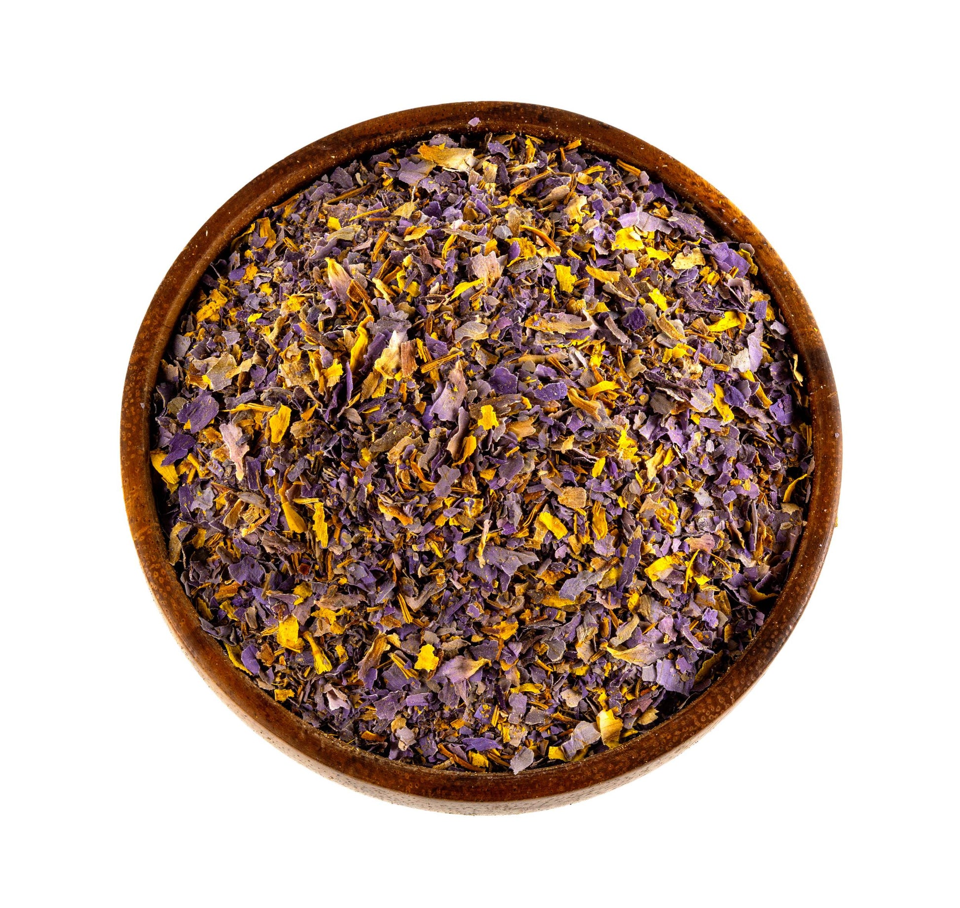 A top-down view of dried blue lotus flower petals and small yellow stamens inside a round wooden bowl, isolated on a white background.