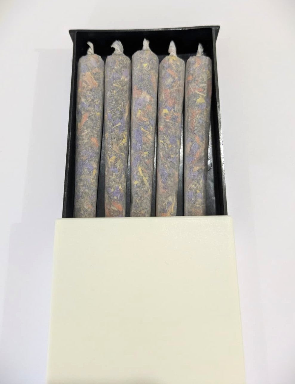Five herbal cigarette pre rolls in a plastic slide box on a white background by Astral Herbal.