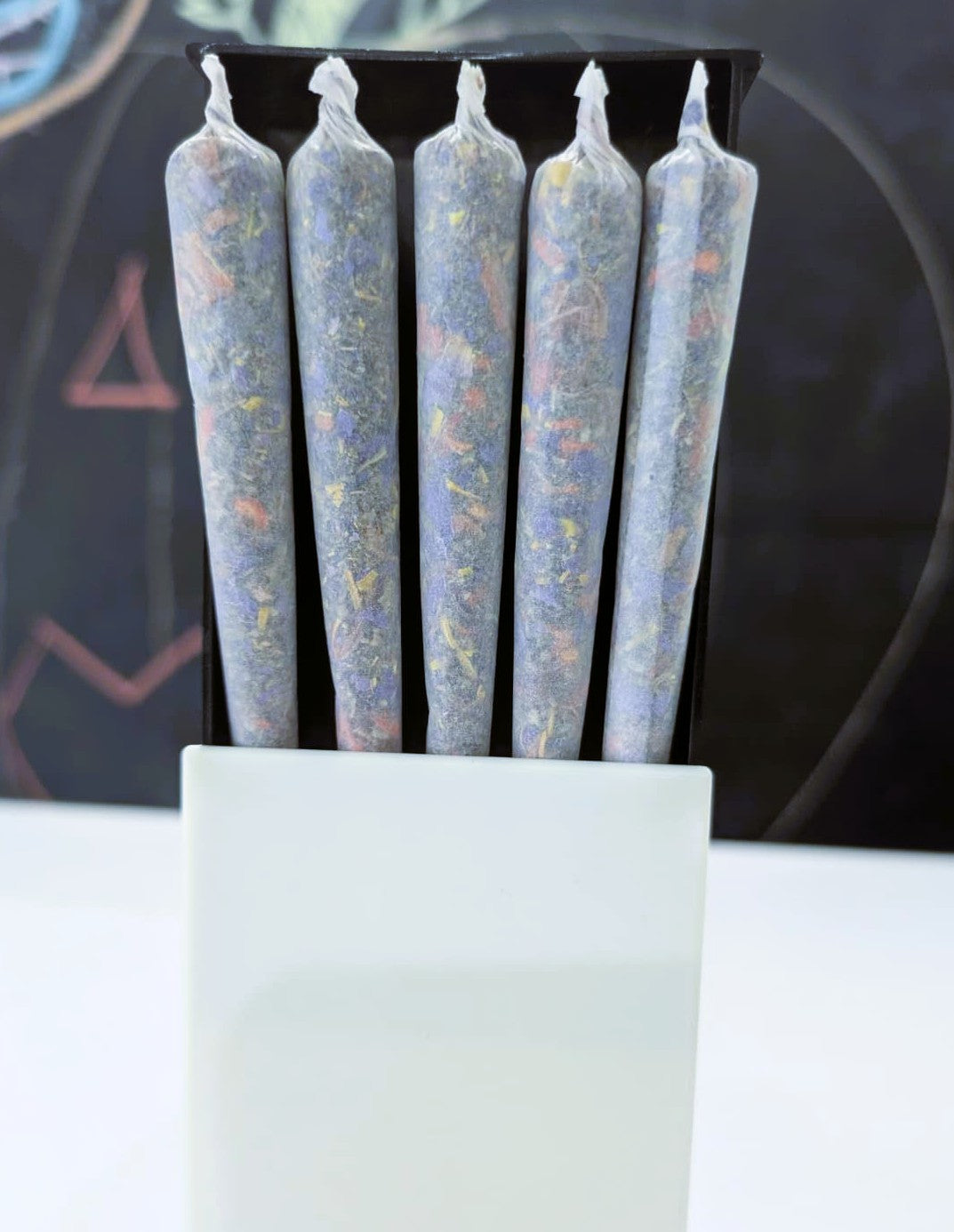Five herbal cigarette pre rolls in a plastic slide box on a white and black background by Astral Herbal.