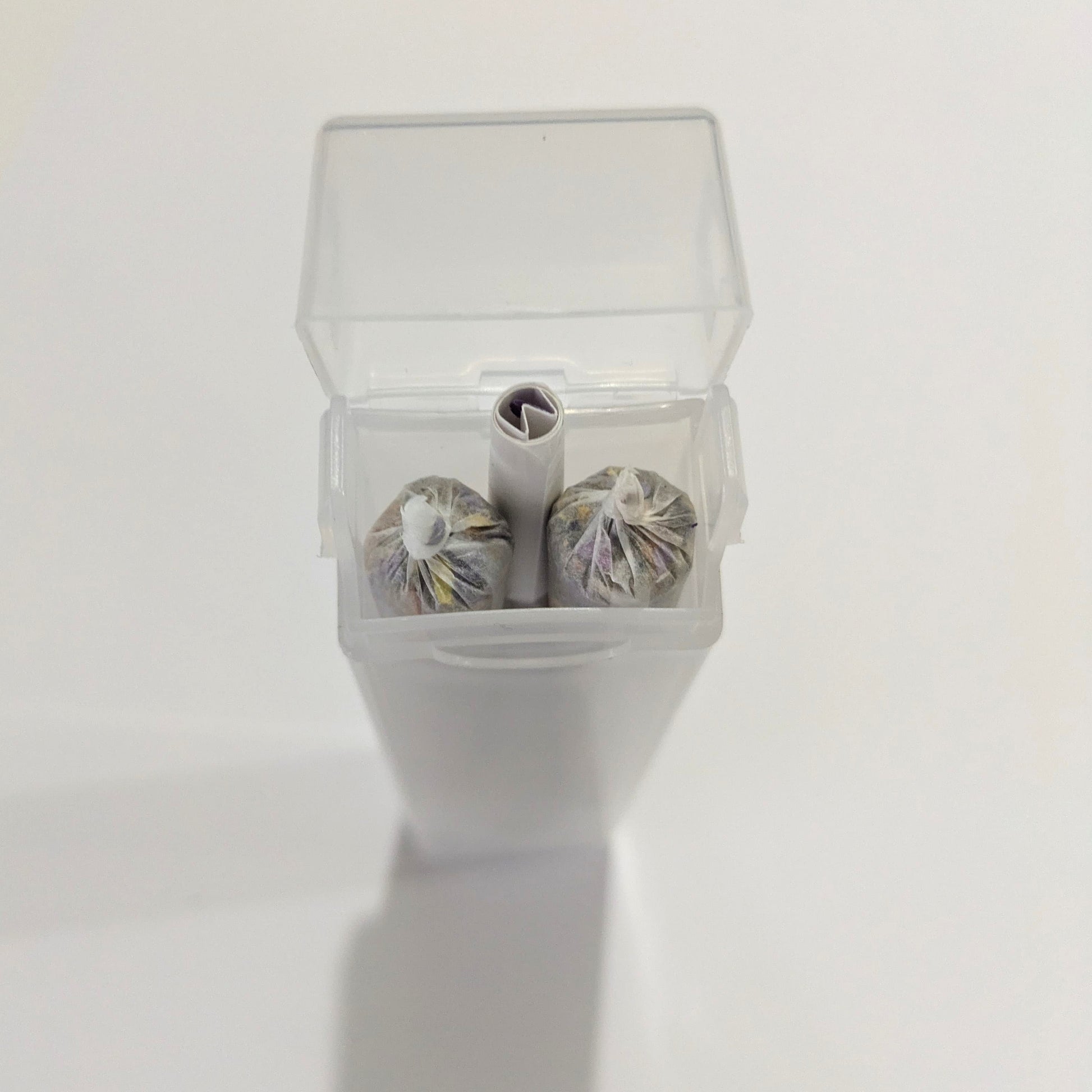 Three herbal cigarette pre rolls in a clear plastic container on a white background by Astral Herbal.
