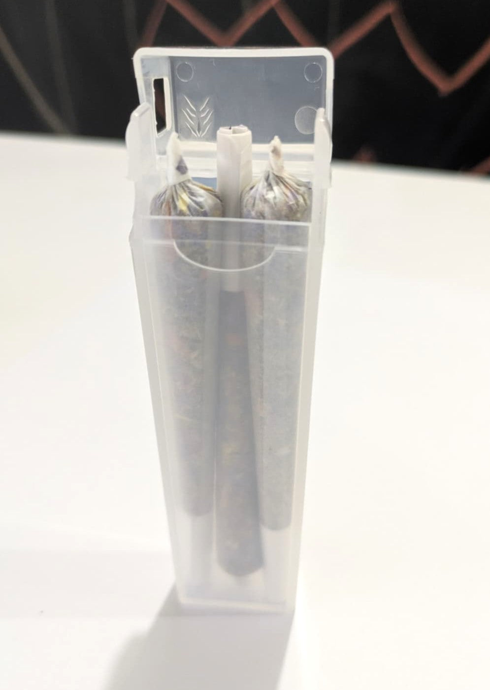 Three herbal cigarette pre rolls in a clear plastic container on a white and black background by Astral Herbal.