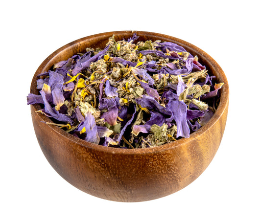 Wooden bowl filled with dried purple and green herbs on a white background