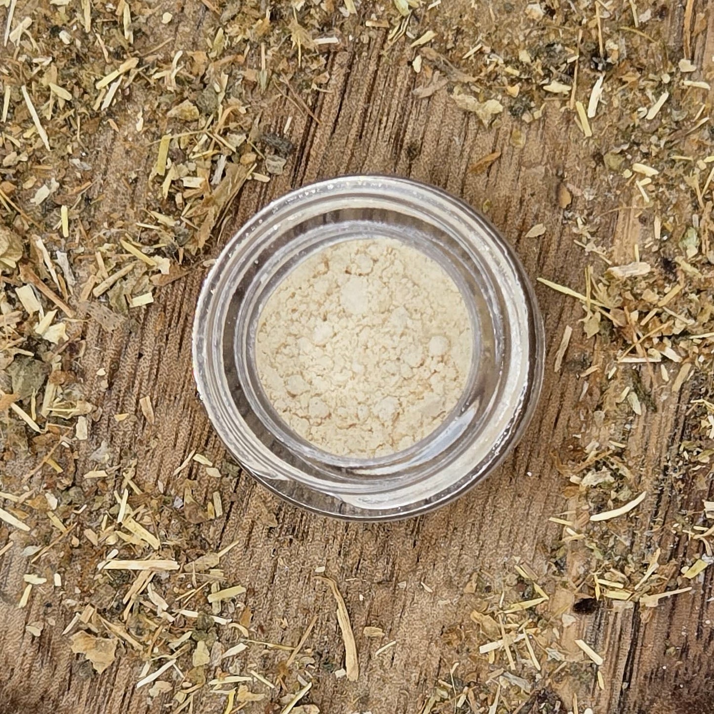 Kanna extract MT-55 in a glass jar on a wooden surface with a background of fermented kanna by Astral Herbal.